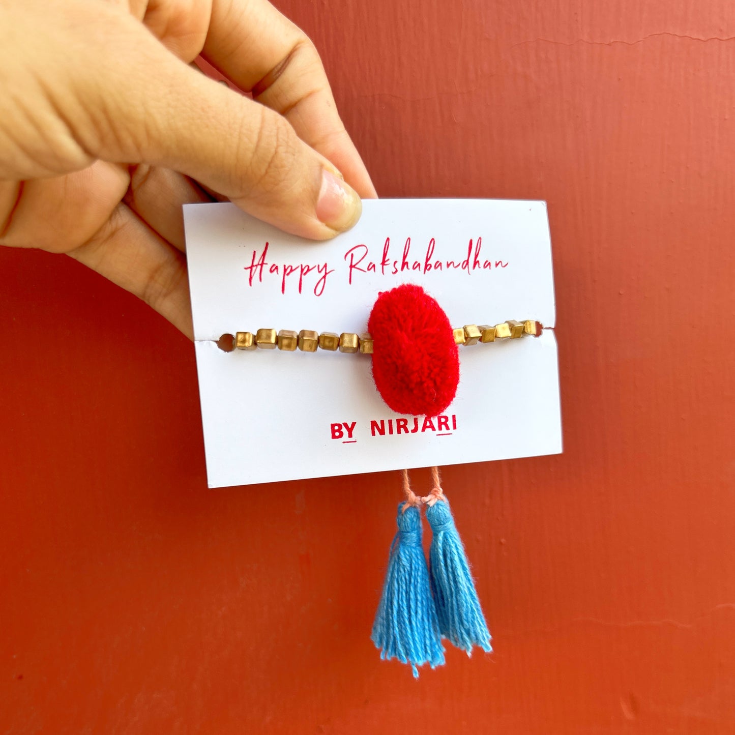 Red pom pom with golden square beads rakhi